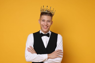 Photo of Handsome man wearing luxury crown on orange background