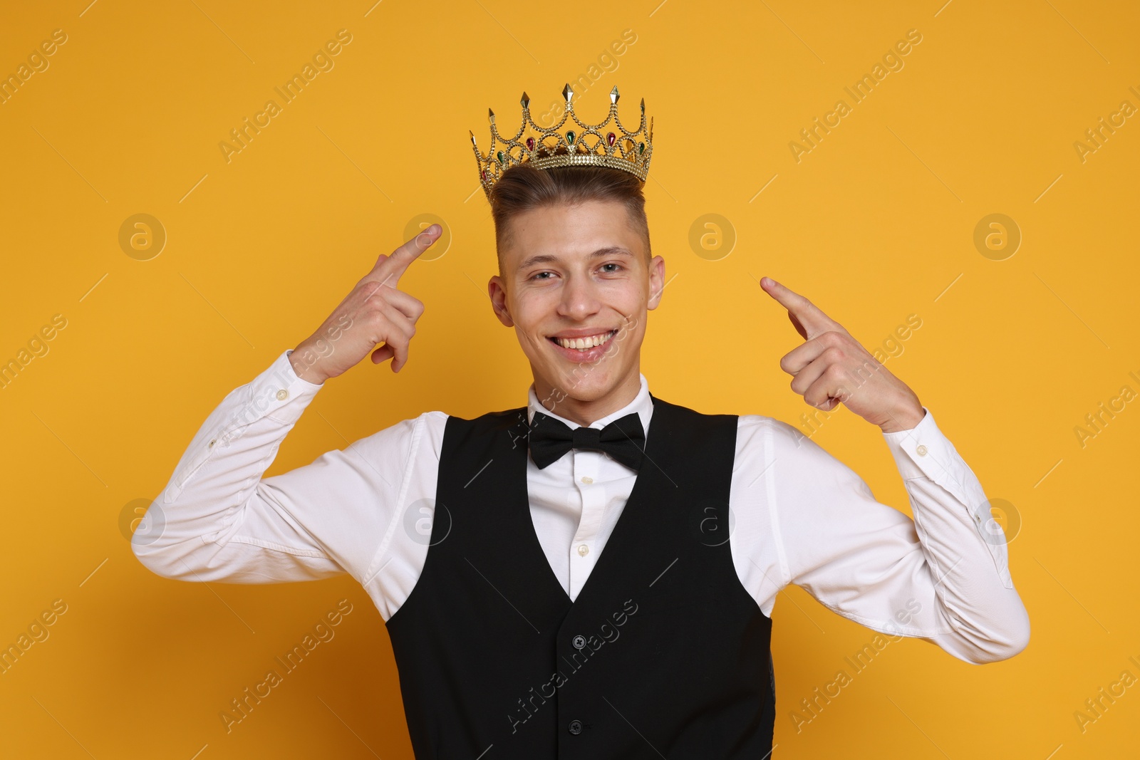 Photo of Handsome man wearing luxury crown on orange background