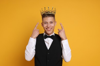 Photo of Handsome man wearing luxury crown on orange background