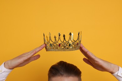 Photo of Man wearing luxury crown on orange background, closeup