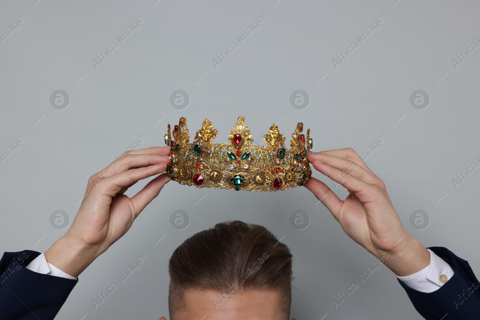 Photo of Man wearing luxury crown on gray background, closeup