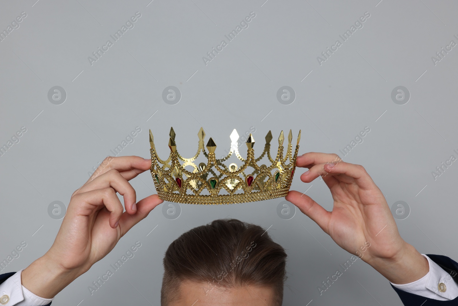 Photo of Man wearing luxury crown on gray background, closeup