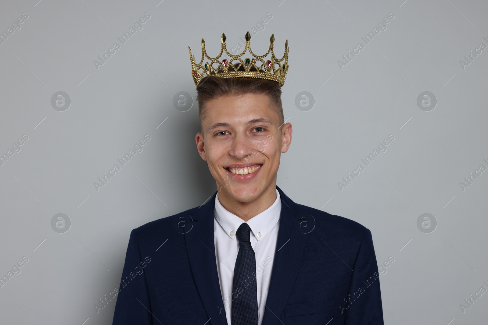 Photo of Handsome man wearing luxury crown on gray background