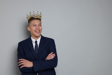 Photo of Handsome man wearing luxury crown on gray background, space for text