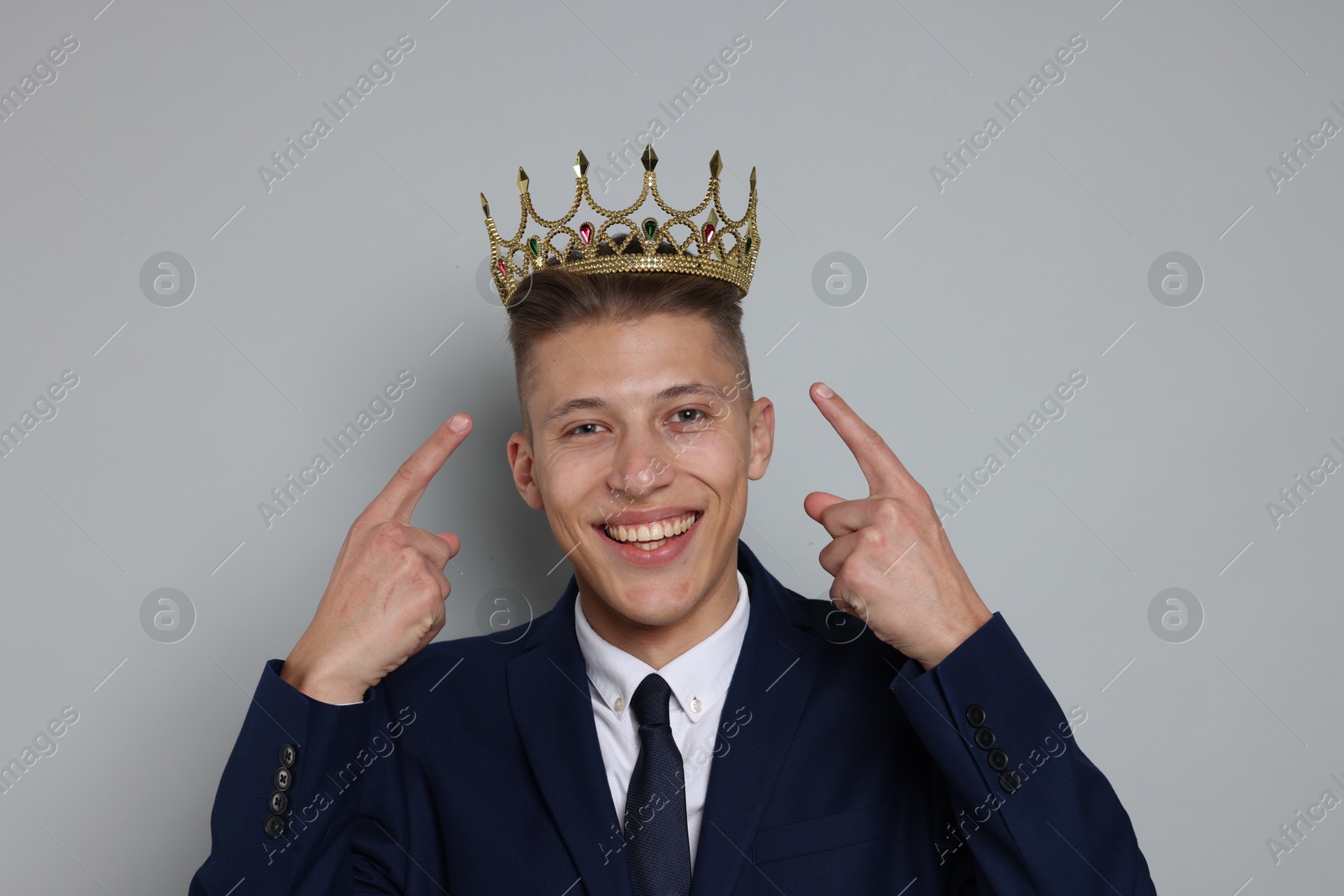 Photo of Handsome man wearing luxury crown on gray background