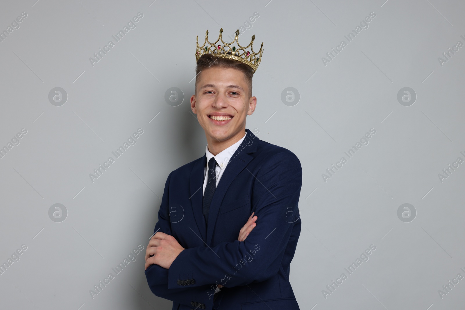 Photo of Handsome man wearing luxury crown on gray background