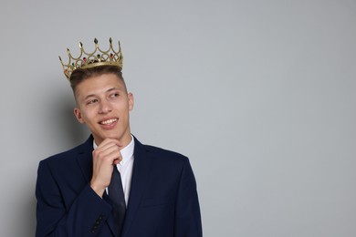 Photo of Handsome man wearing luxury crown on gray background, space for text