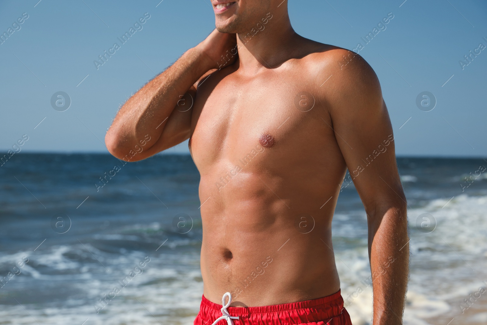 Photo of Man with attractive body on beach, closeup