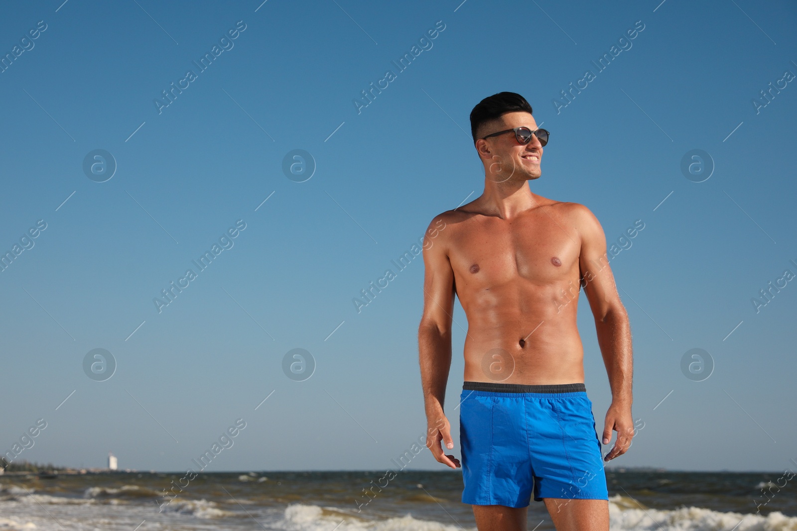 Photo of Handsome man with attractive body on beach. Space for text