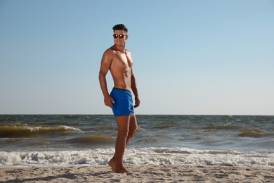 Photo of Handsome man with attractive body on beach