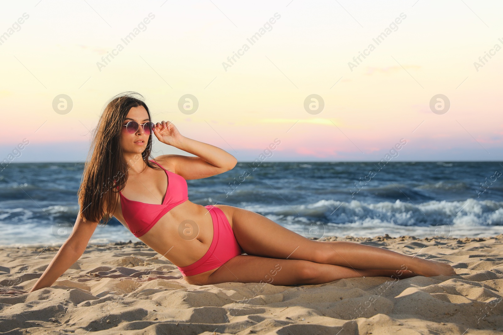 Photo of Beautiful young woman with attractive body posing on sandy beach