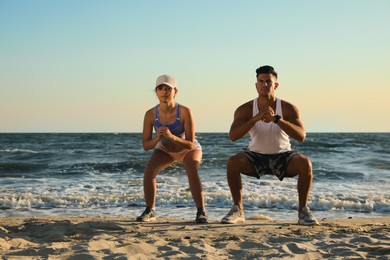 Photo of Sporty couple doing exercise on beach at sunset