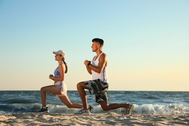 Photo of Sporty couple doing exercise on beach at sunset