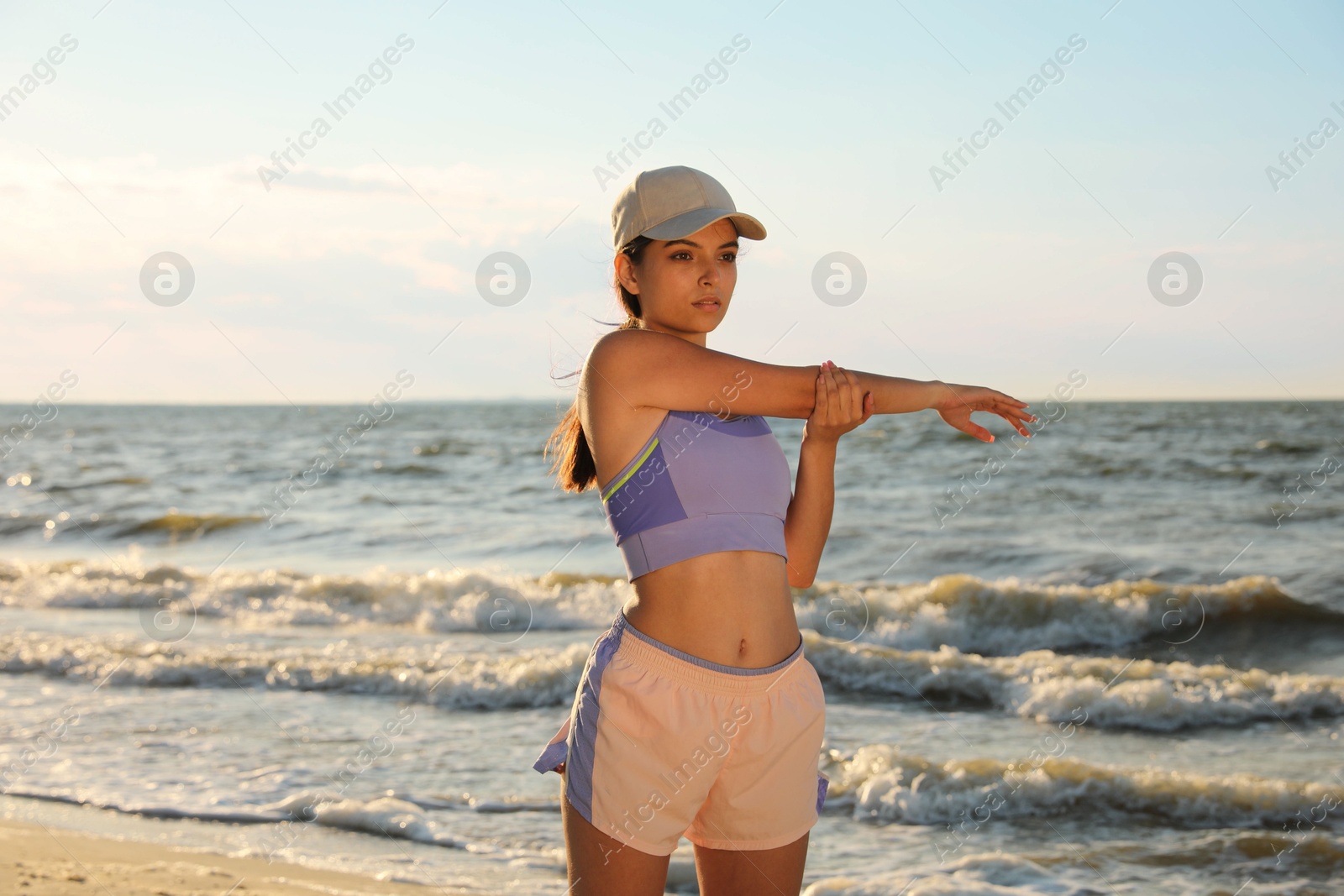 Photo of Young woman doing exercise on beach at sunset