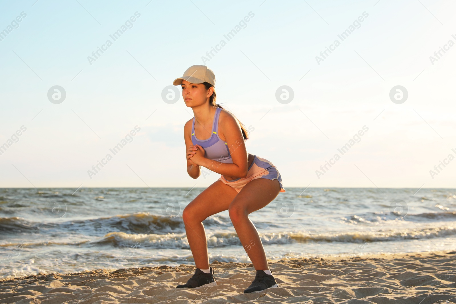 Photo of Young woman doing exercise on beach at sunset