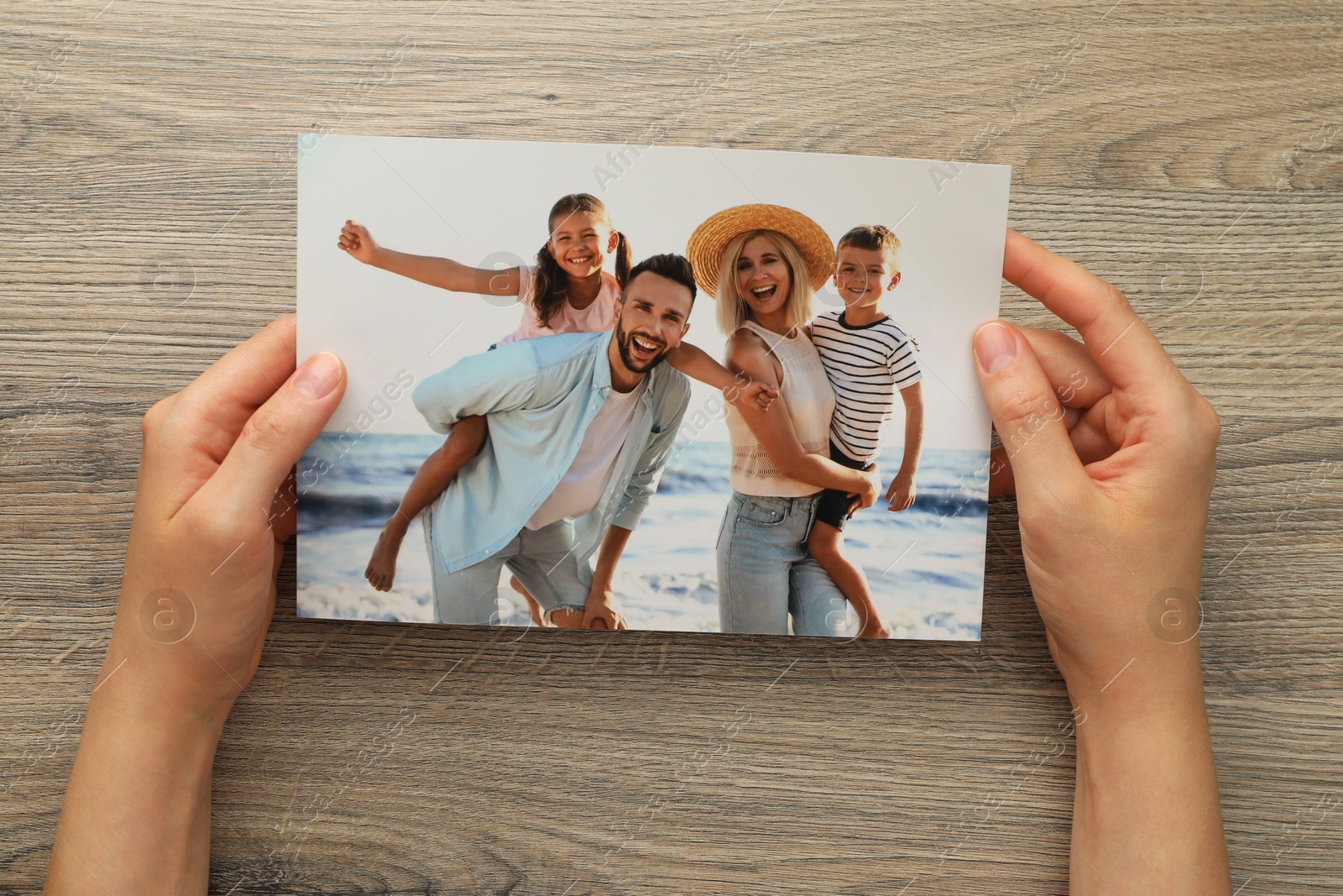 Photo of Woman with family photo at wooden table, top view