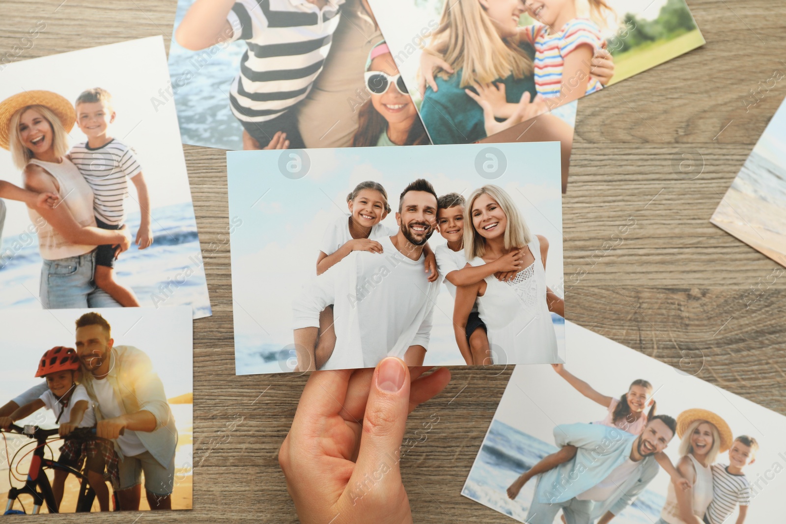 Photo of Woman with different photos at wooden table, top view