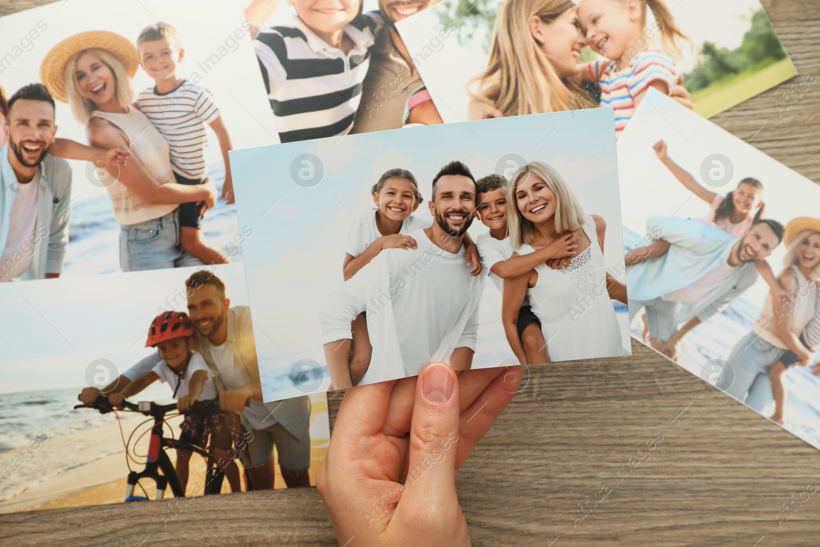 Photo of Woman with different photos at wooden table, top view