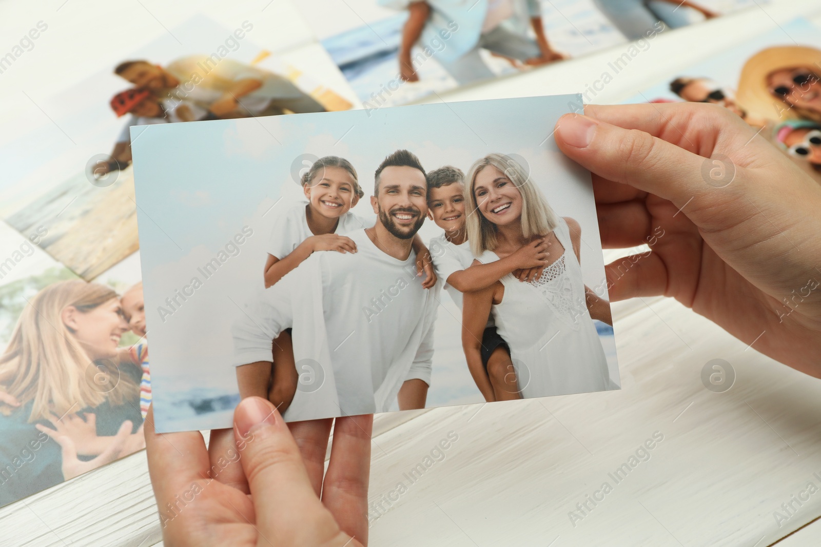 Photo of Woman with different photos at white wooden table, closeup