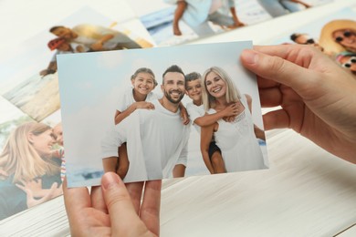 Photo of Woman with different photos at white wooden table, closeup