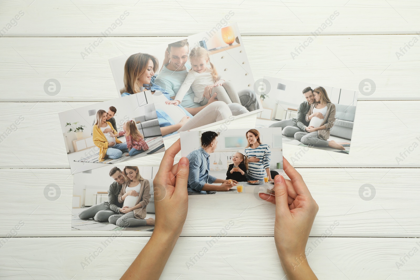 Photo of Woman with different photos at white wooden table, top view