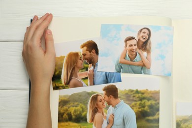 Photo of Woman with different photos in open photo album at white wooden table, top view