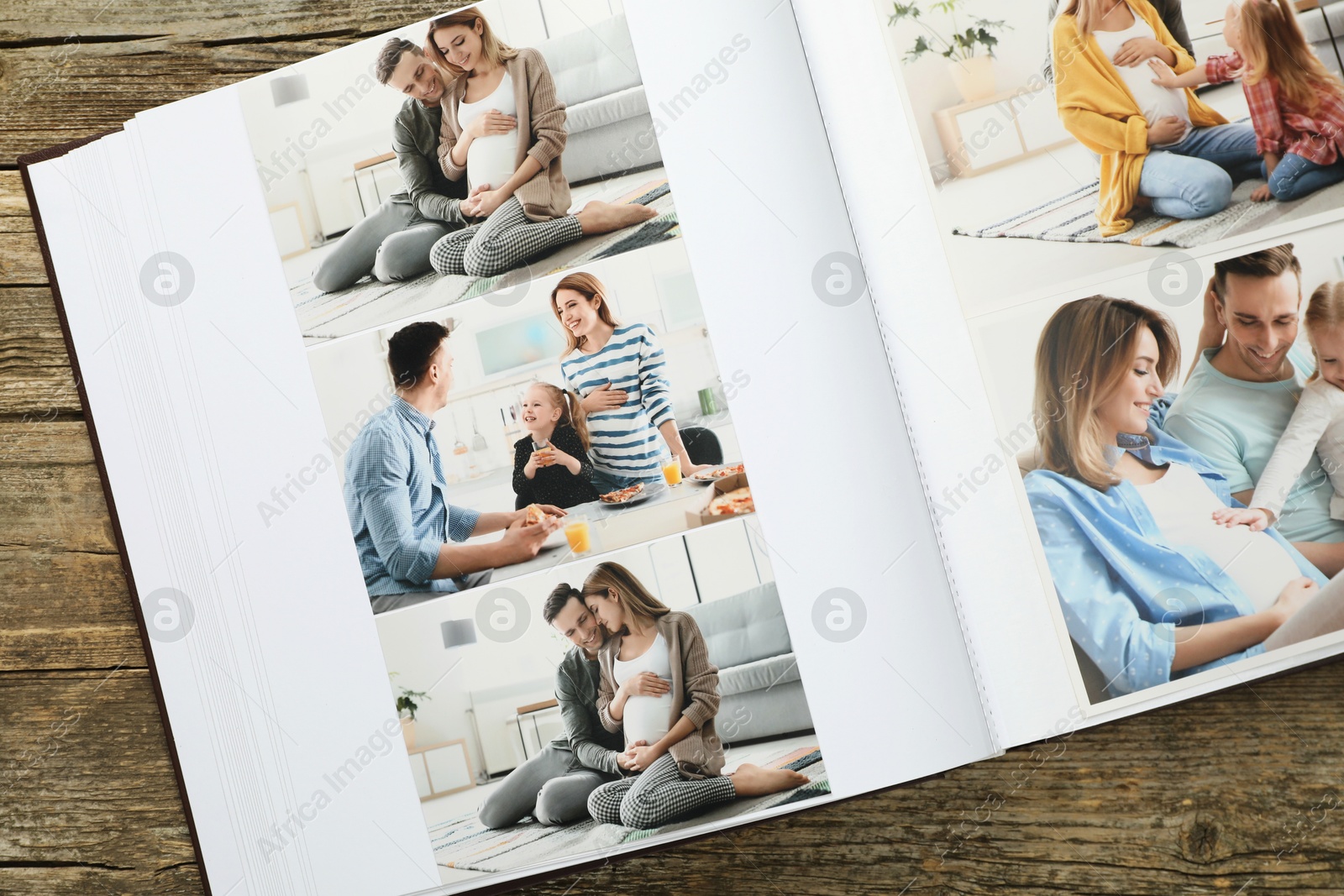 Photo of Different photos in open photo album on wooden table, top view