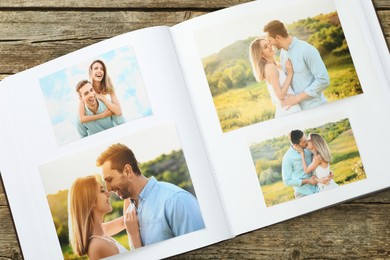 Photo of Different photos in open photo album on wooden table, top view