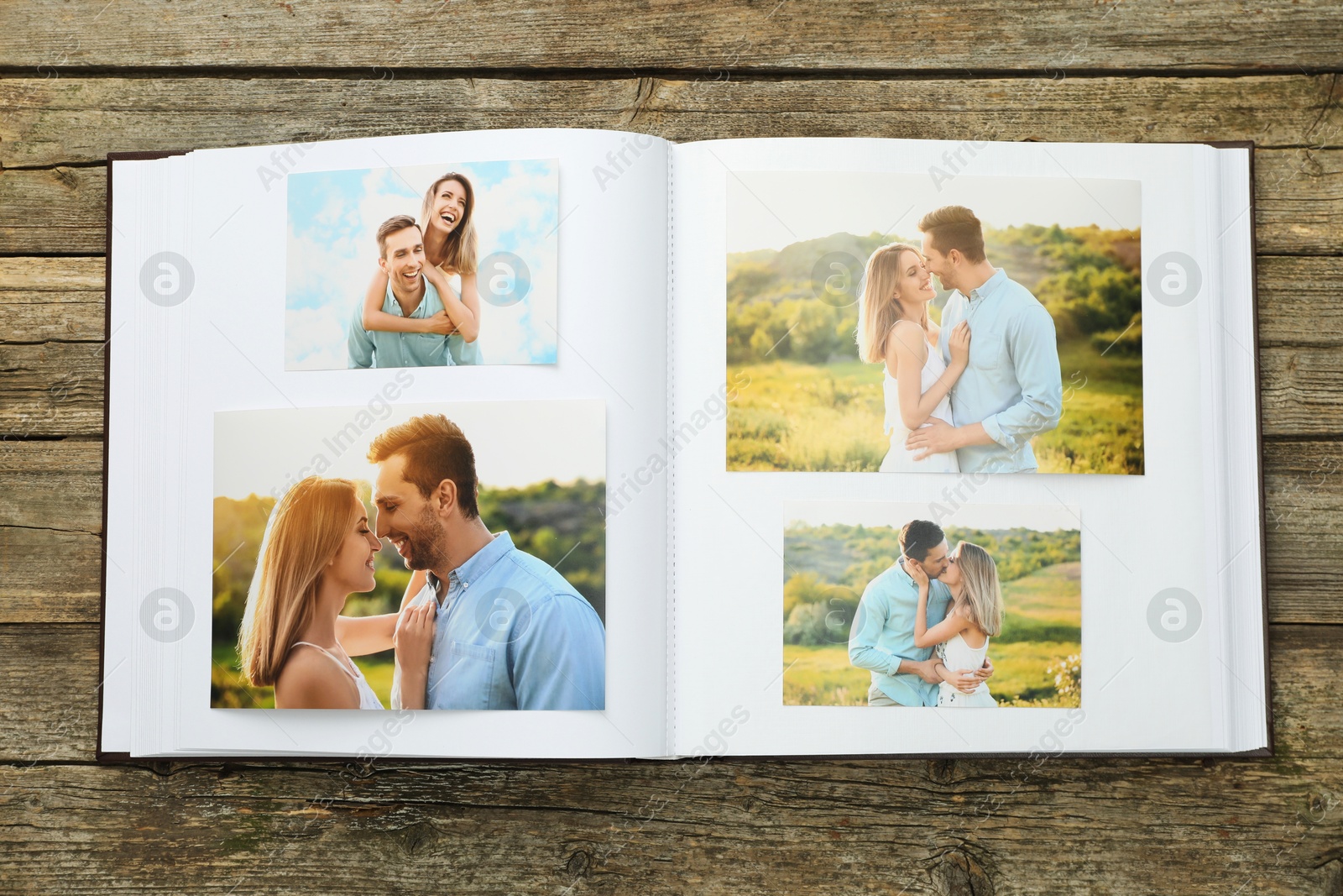 Photo of Different photos in open photo album on wooden table, top view