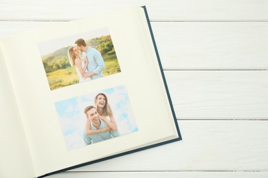 Photo of Different photos in open photo album on white wooden table, top view. Space for text