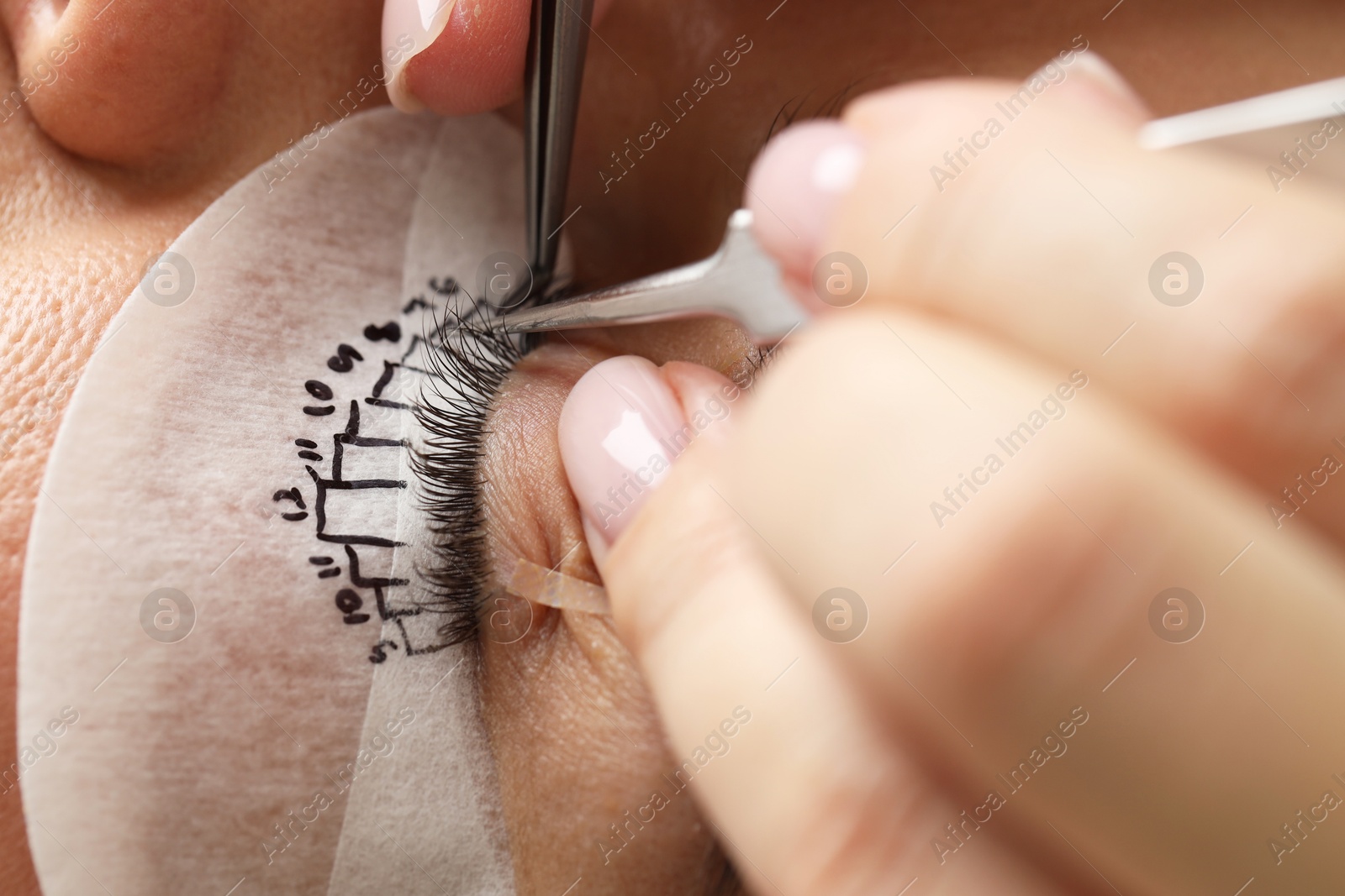 Photo of Young woman undergoing lash extensions procedure, closeup