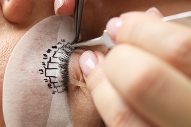 Photo of Young woman undergoing lash extensions procedure, closeup