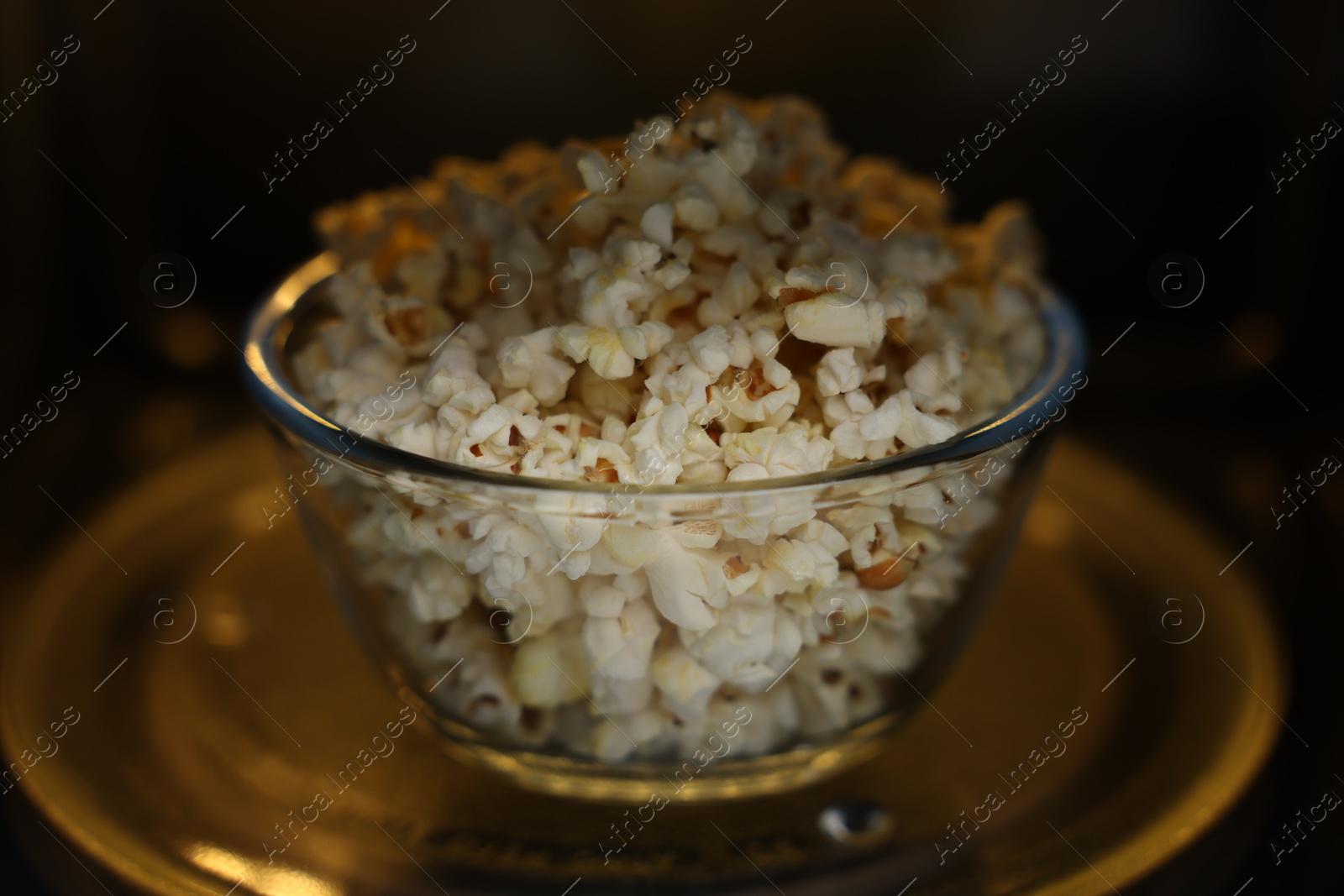 Photo of Bowl of tasty popcorn in microwave oven, closeup