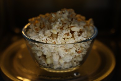 Photo of Bowl of tasty popcorn in microwave oven, closeup