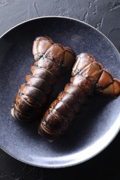 Photo of Raw lobster tails on black table, top view