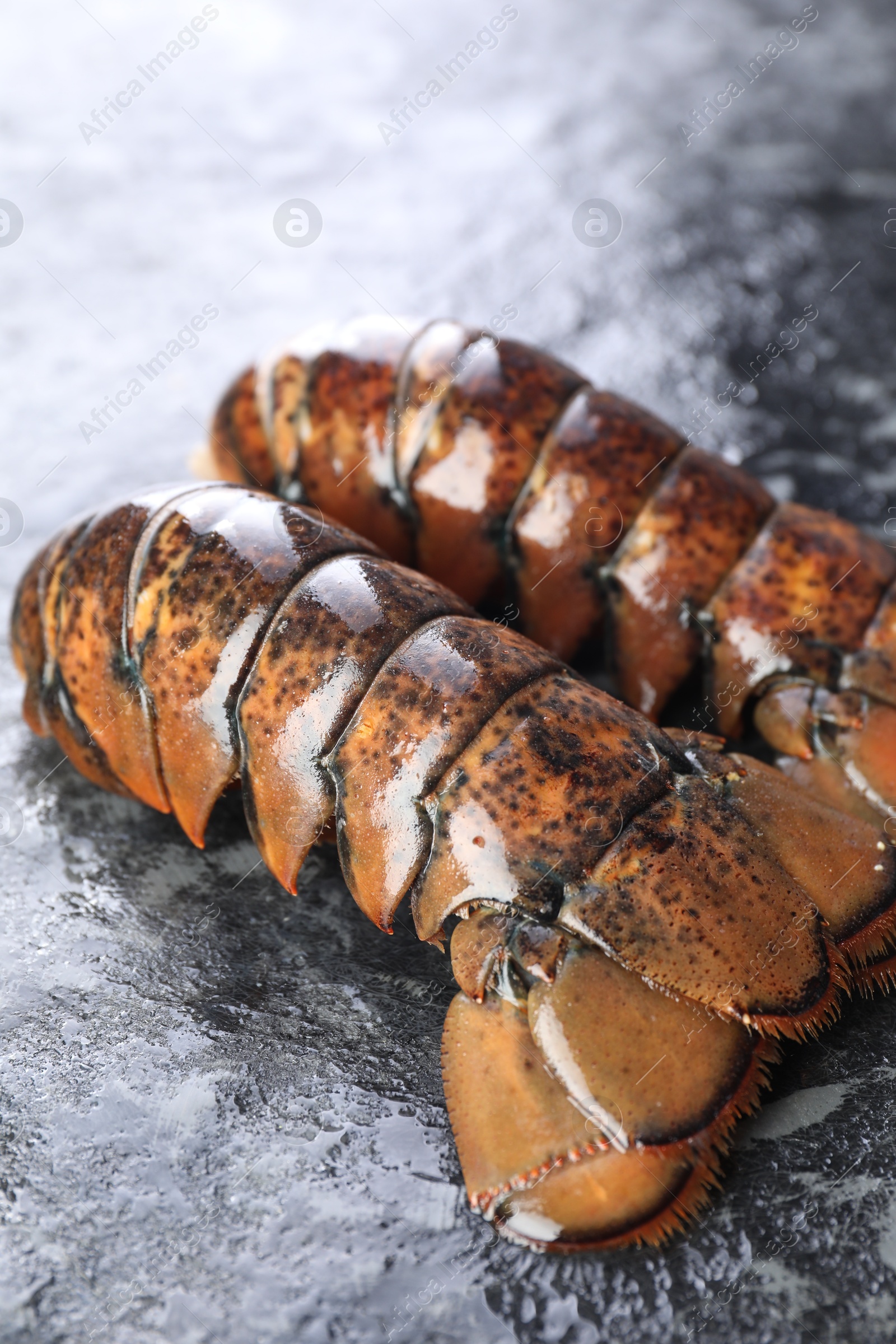 Photo of Raw lobster tails on dark table, closeup