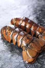 Photo of Raw lobster tails on dark table, closeup