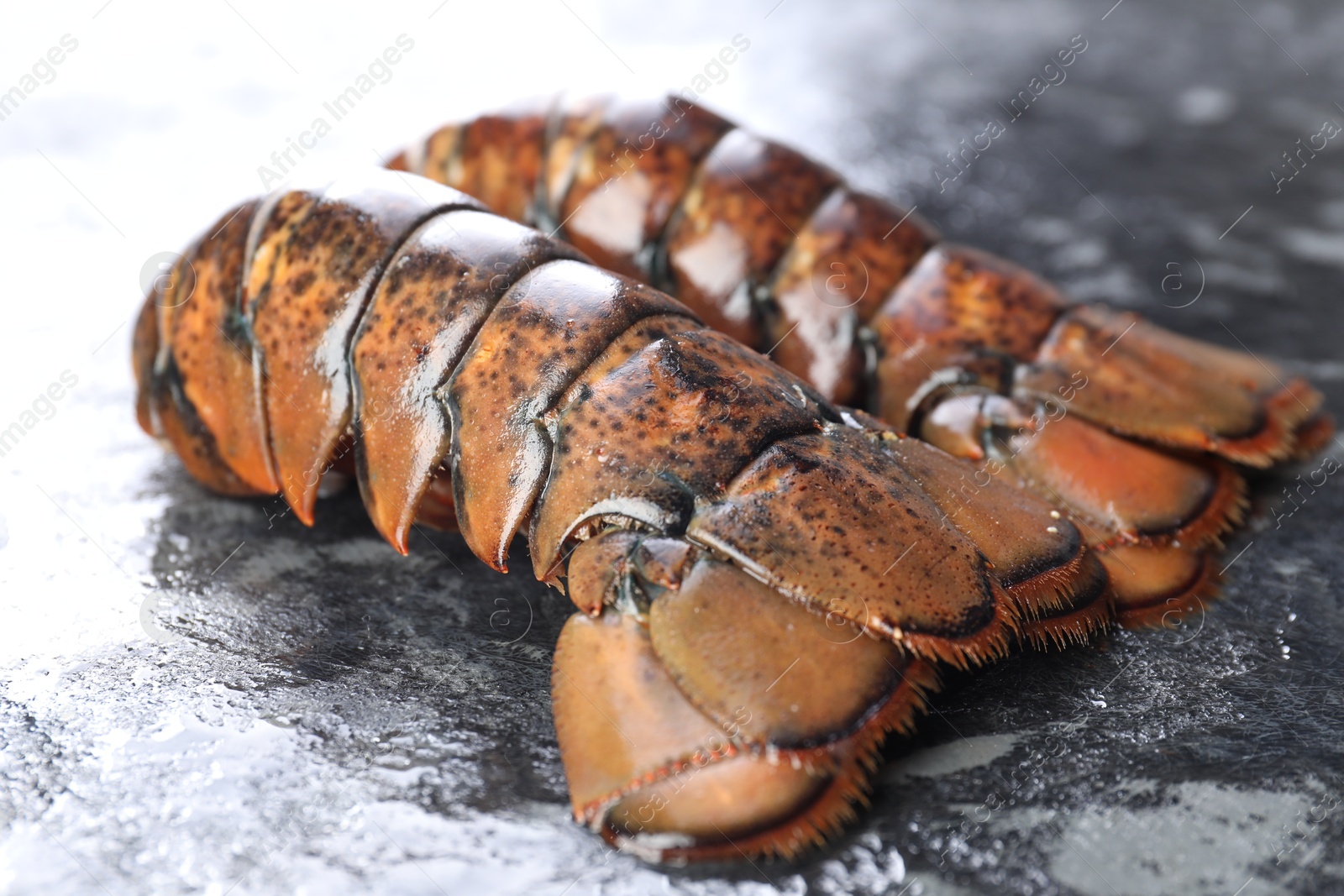 Photo of Raw lobster tails on dark table, closeup