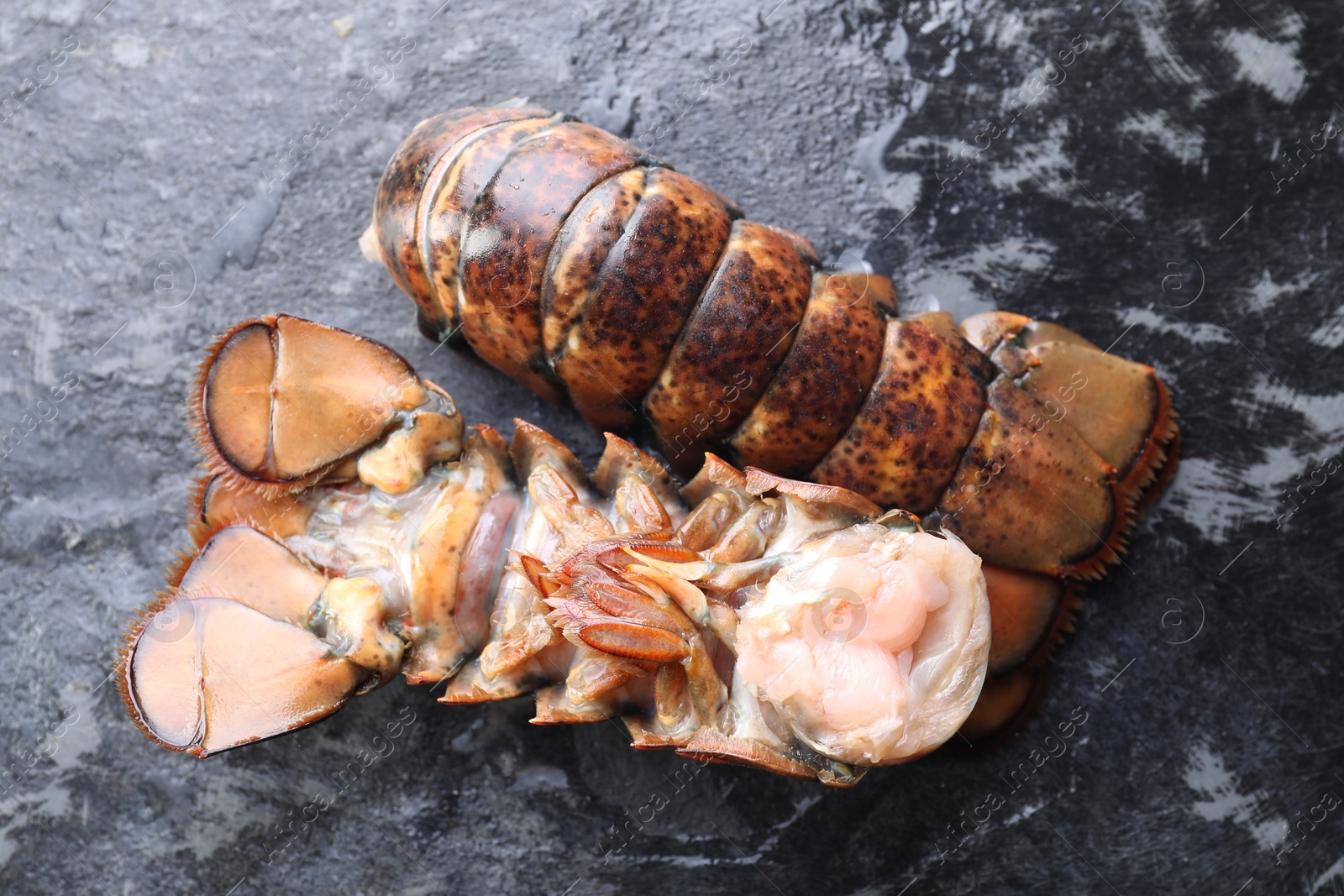 Photo of Raw lobster tails on dark table, flat lay