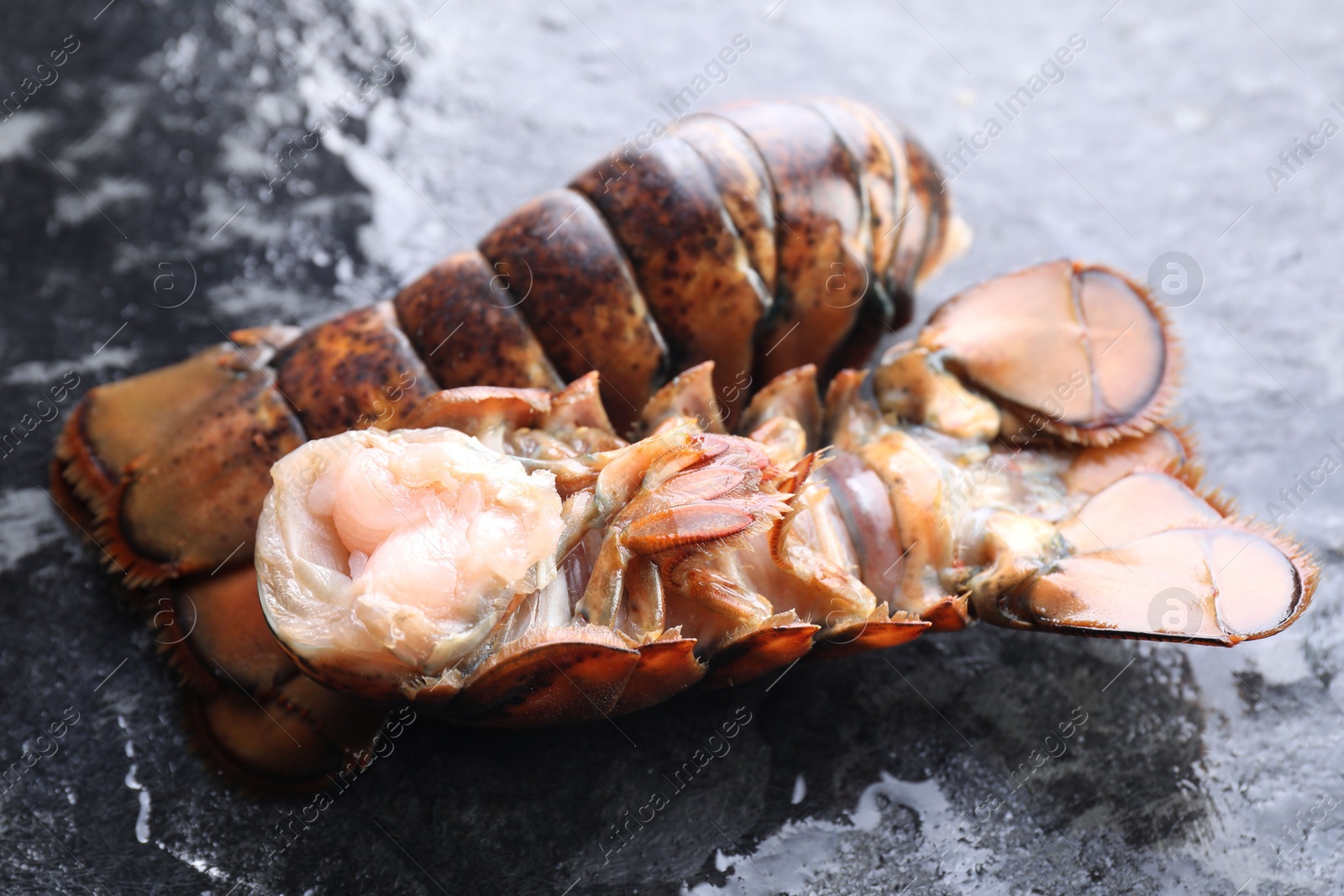 Photo of Raw lobster tails on dark table, closeup