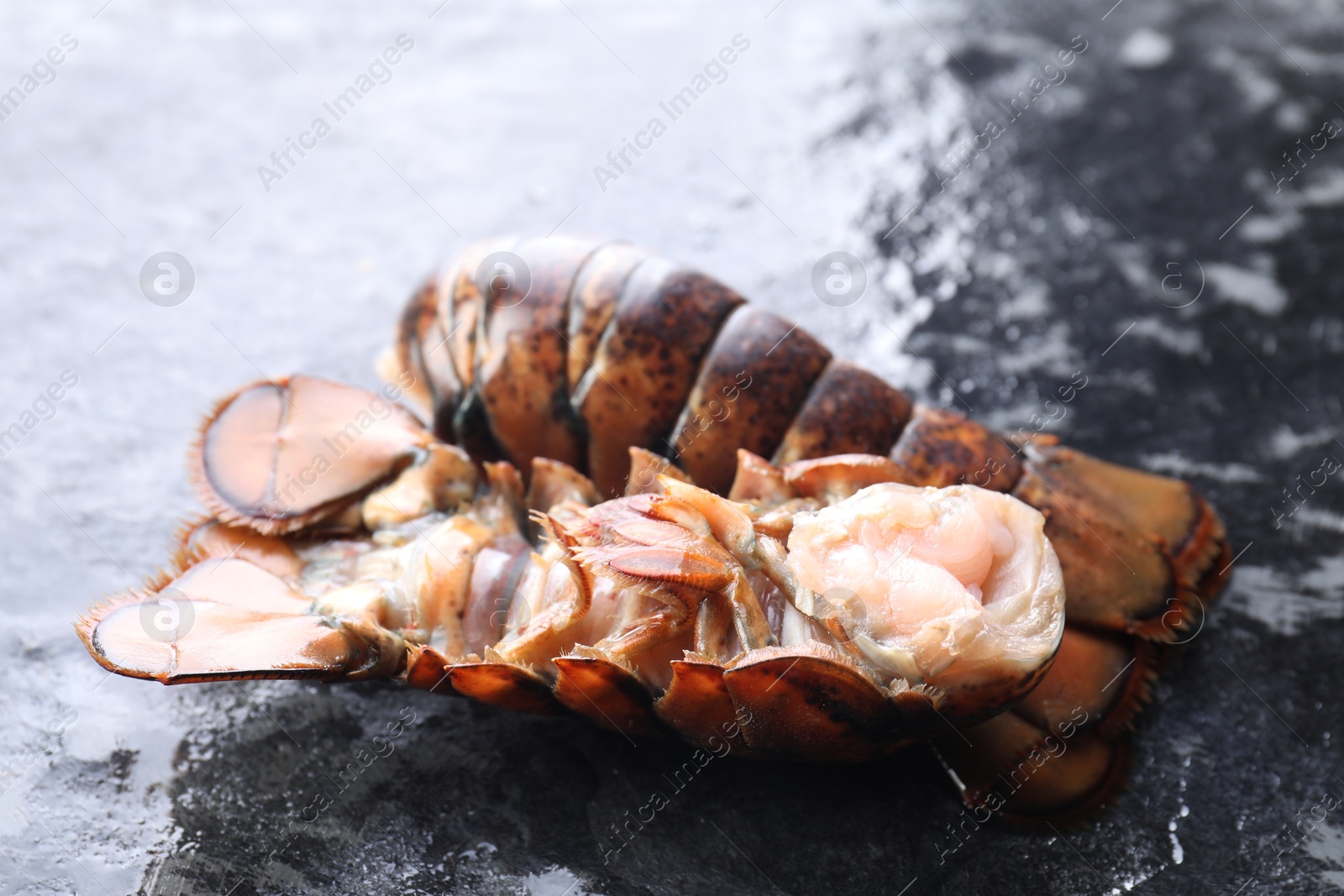 Photo of Raw lobster tails on dark table, closeup