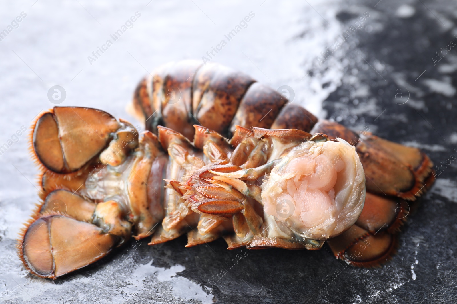 Photo of Raw lobster tails on dark table, closeup