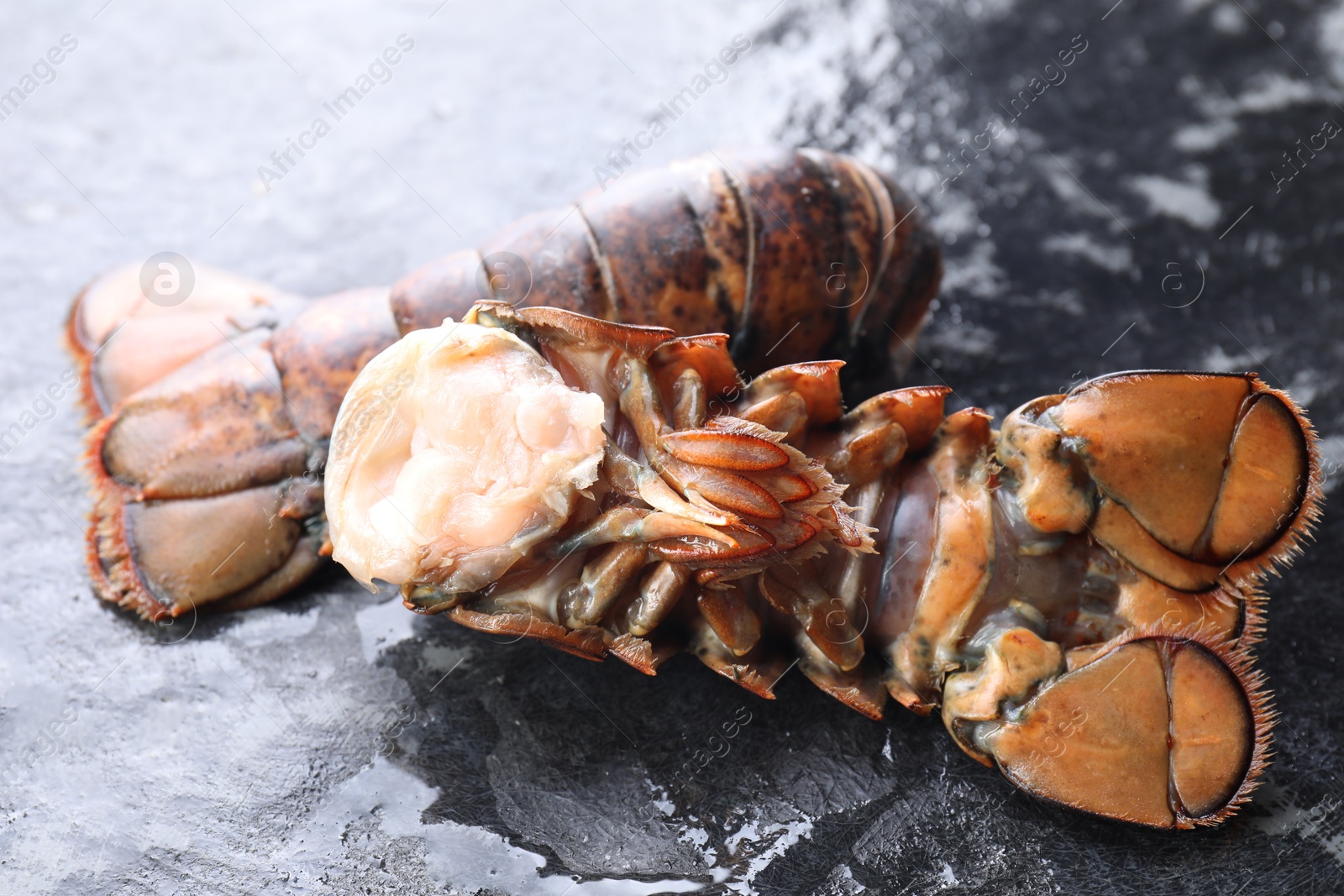 Photo of Raw lobster tails on dark table, closeup