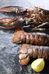 Photo of Raw lobster, tails and lime on dark table, closeup