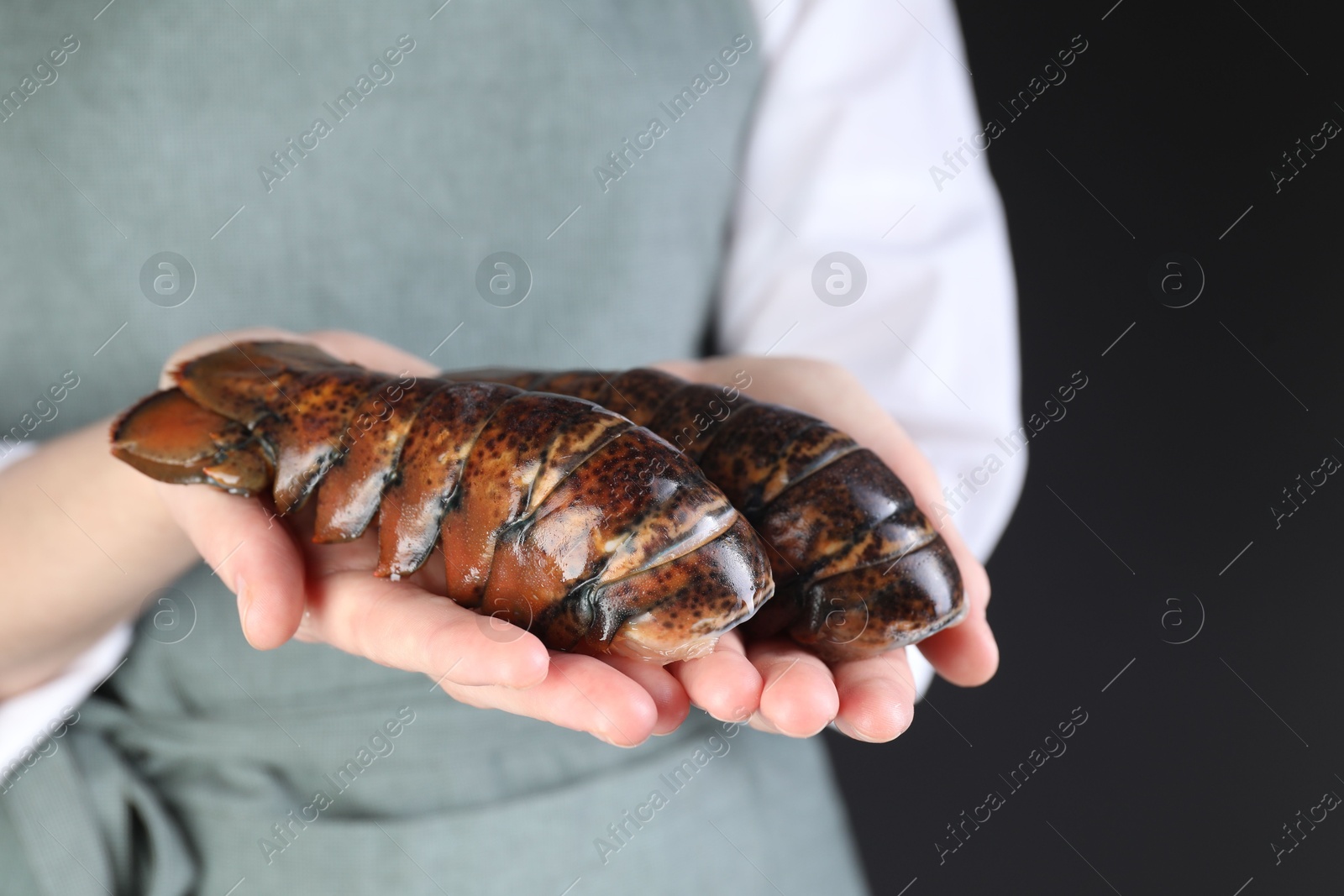 Photo of Woman with raw lobster tails on black background, closeup