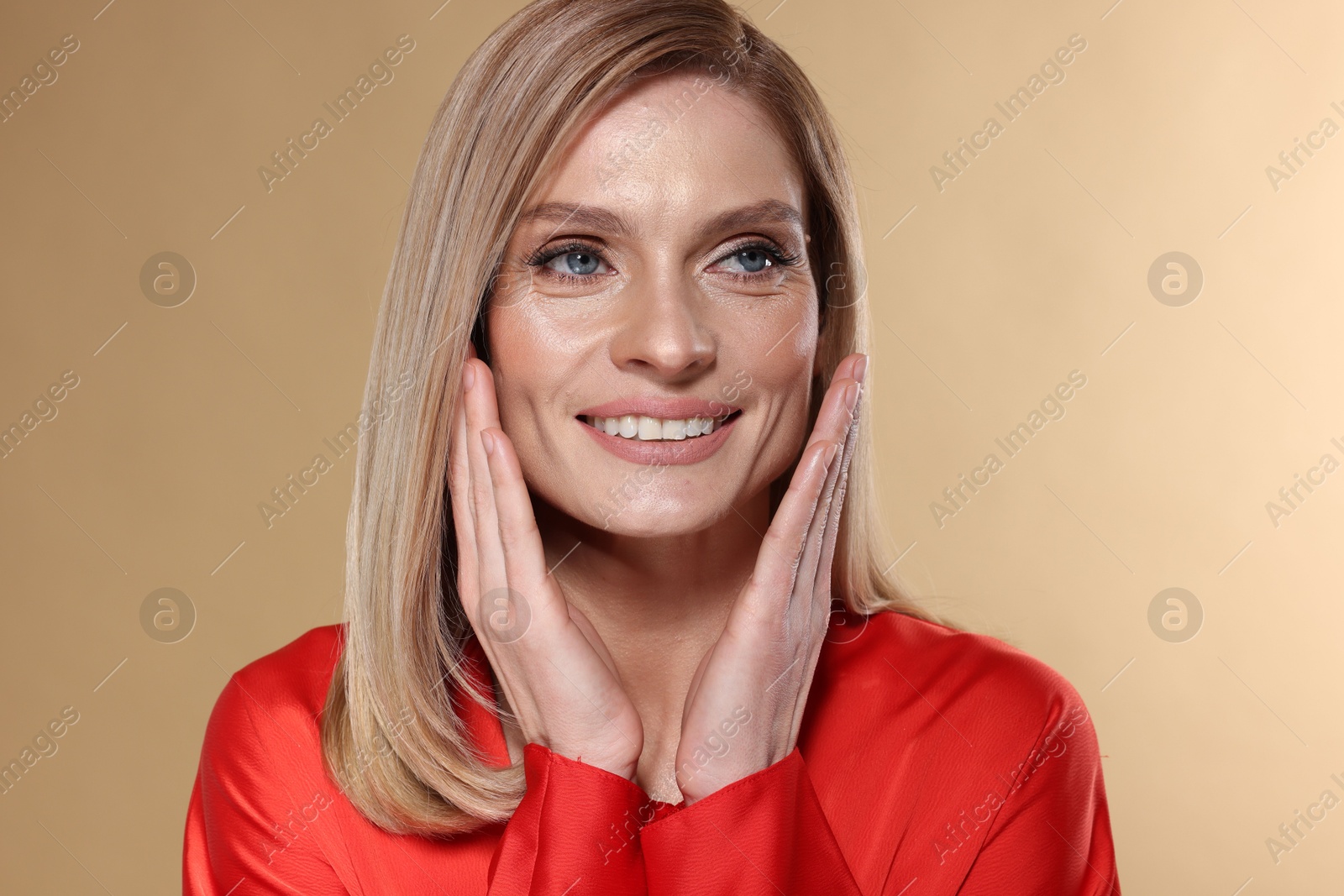 Photo of Portrait of beautiful happy woman with straight blonde hair on beige background