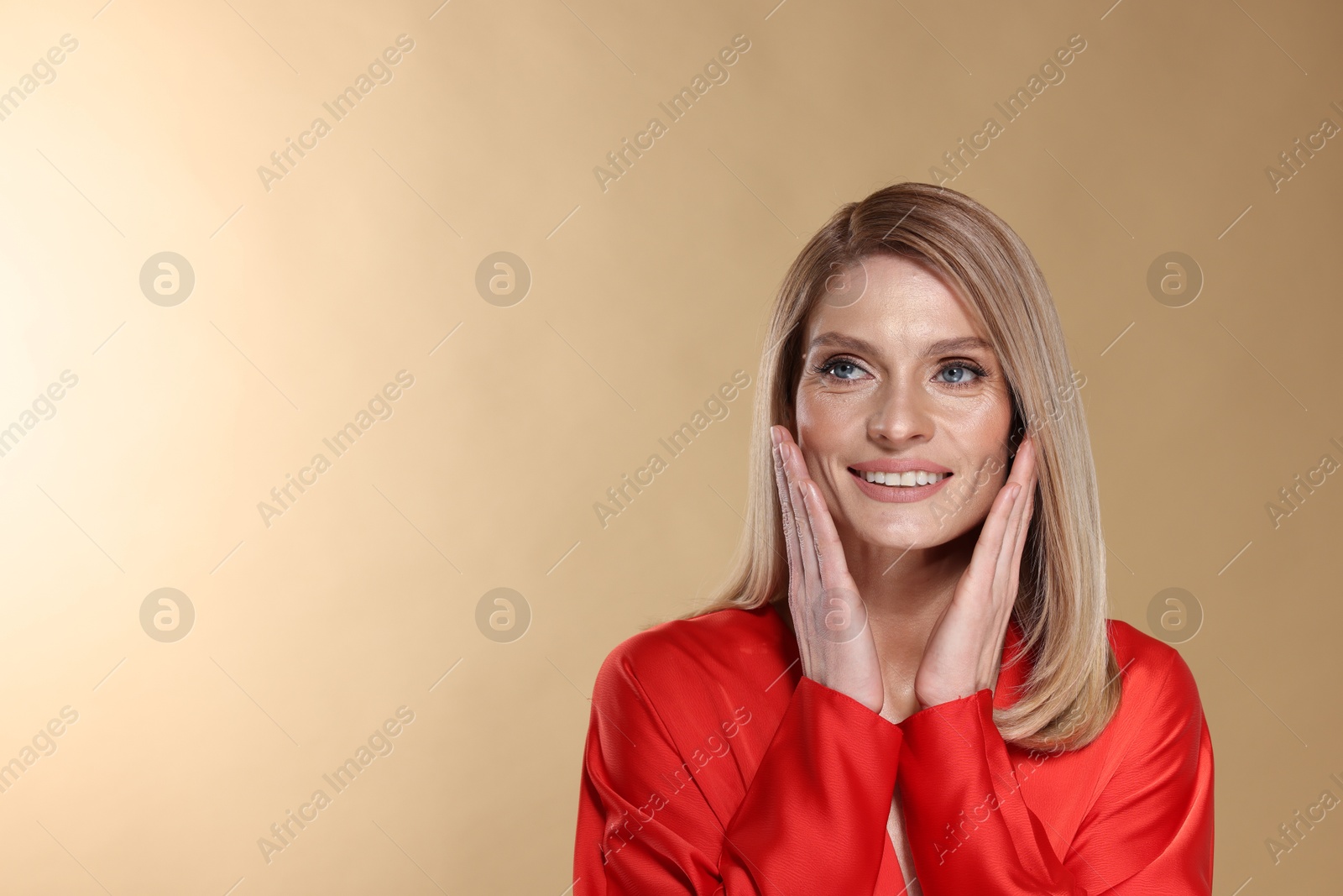 Photo of Portrait of beautiful happy woman with straight blonde hair on beige background, space for text