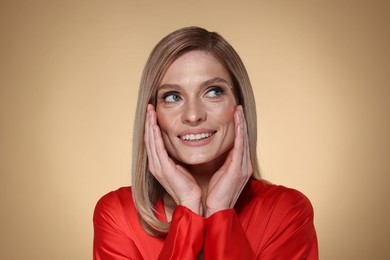 Photo of Portrait of beautiful happy woman with straight blonde hair on beige background