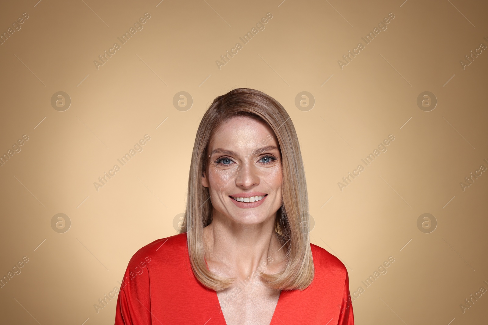 Photo of Portrait of beautiful happy woman with straight blonde hair on beige background