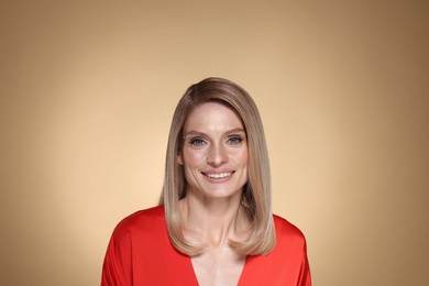 Photo of Portrait of beautiful happy woman with straight blonde hair on beige background